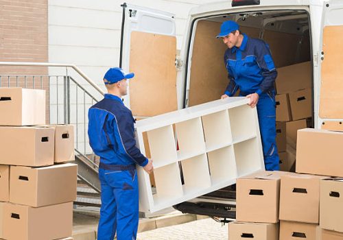 Young male movers unloading furniture and cardboard boxes from truck on street Young male movers unloading furniture and cardboard boxes from truck on street